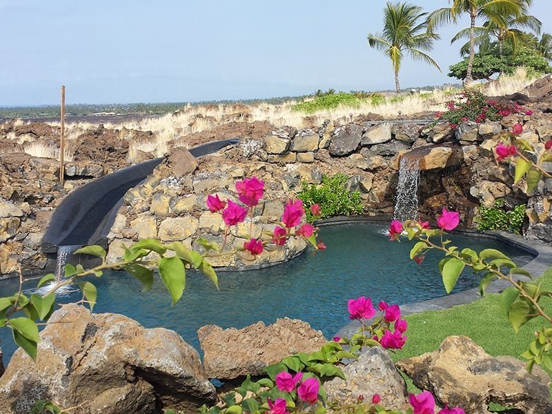 Custom Hawaii pool design with natural rocks, flora, and waterfalls.